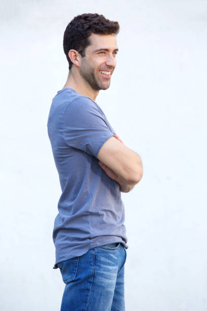 istock Handsome young man standing with arms crossed against white wall 911867376