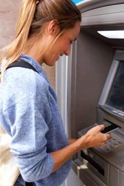 istock young woman with mobile phone by bank machine 911870462