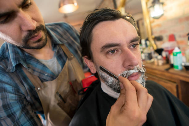 istock Man shaving his beard at a barber shop 911870676