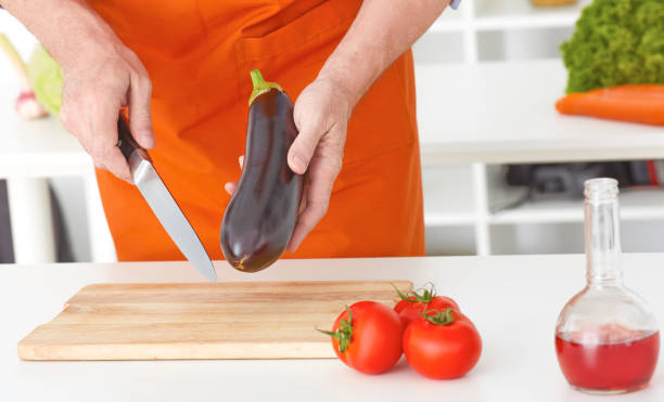 gros plan homme mains légumes coupe sur une surface de travail dans une cuisine. un régime de concept. mode de vie sain. cuisiner à la maison. préparer les aliments. - eggplant vegetable food close up photos et images de collection