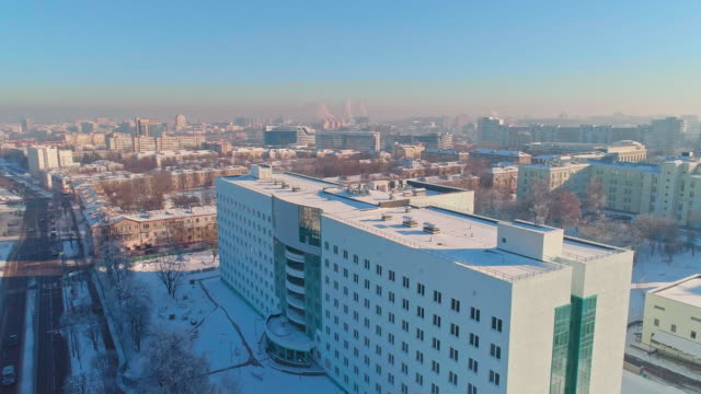 The aerial panoramic view on the winter city covered by the snow in the bright cold sunny day. Orbit camera motion.