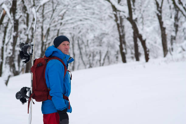 istock Adventurer with snowboard and backpack stands in the forest 911879170