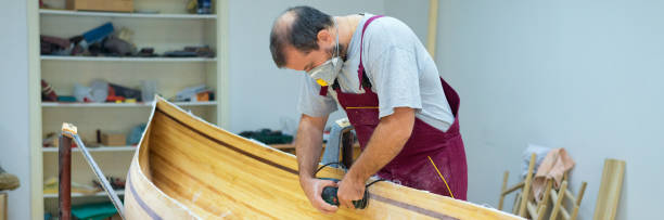 istock Carpenter making wooden canoe boat 911885652