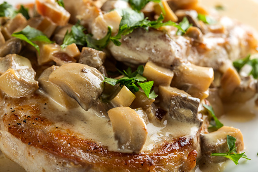Close up of pork sirloin with white sauce made from sour cream and mushrooms with parsley