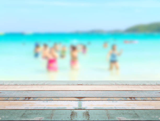 istock Wood table top with blurred people at the beach 911898484