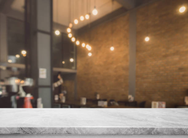 istock White stone marble table top and blurred bokeh cafe and coffee shop interior background with vintage filter - can used for display or montage your products. 911901328