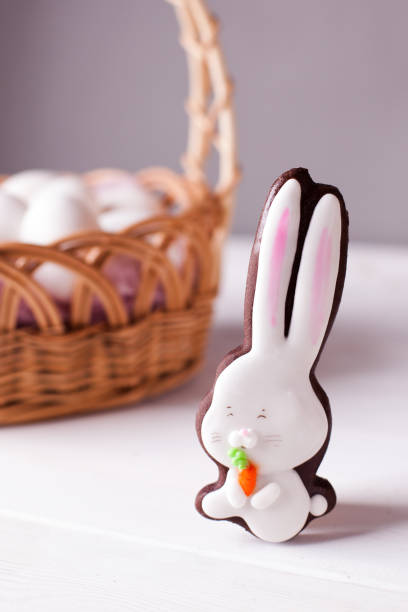 istock Easter background - gingerbread rabbit with sugar glaze on background of Easter basket with white eggs 911904026