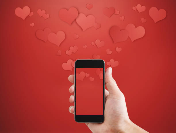 istock Hand holding mobile smart phone, with floating hearts. Valentines, love message and texting 911911060