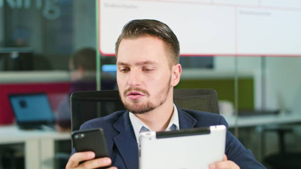 istock Young Man Using a Phone and a Tablet in the Office 911921392