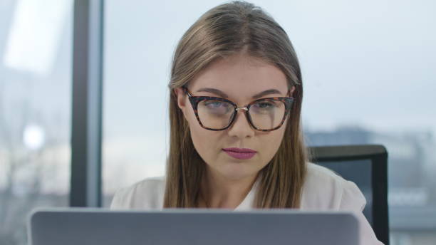 istock Young Lady with Glasses Looking at the Laptop 911921648