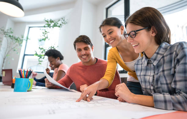 istock Group of designers pointing at some blueprints at a creative office 911928484