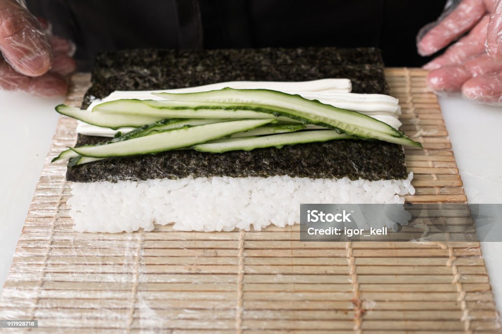 chef prepare sushi roll fresh cucumber ingredients This is tasty. Chef prepares sushi rolling cucumbers in rice and nori. Fresh ingredients concept Chef Stock Photo