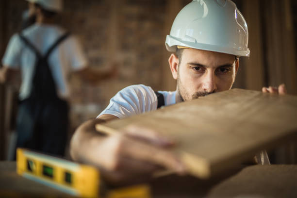 Young carpenter examining if everything is ok with wooden plank during home improvement process.