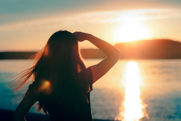 donna felice speranza guardando il tramonto in mare - destinies foto e immagini stock