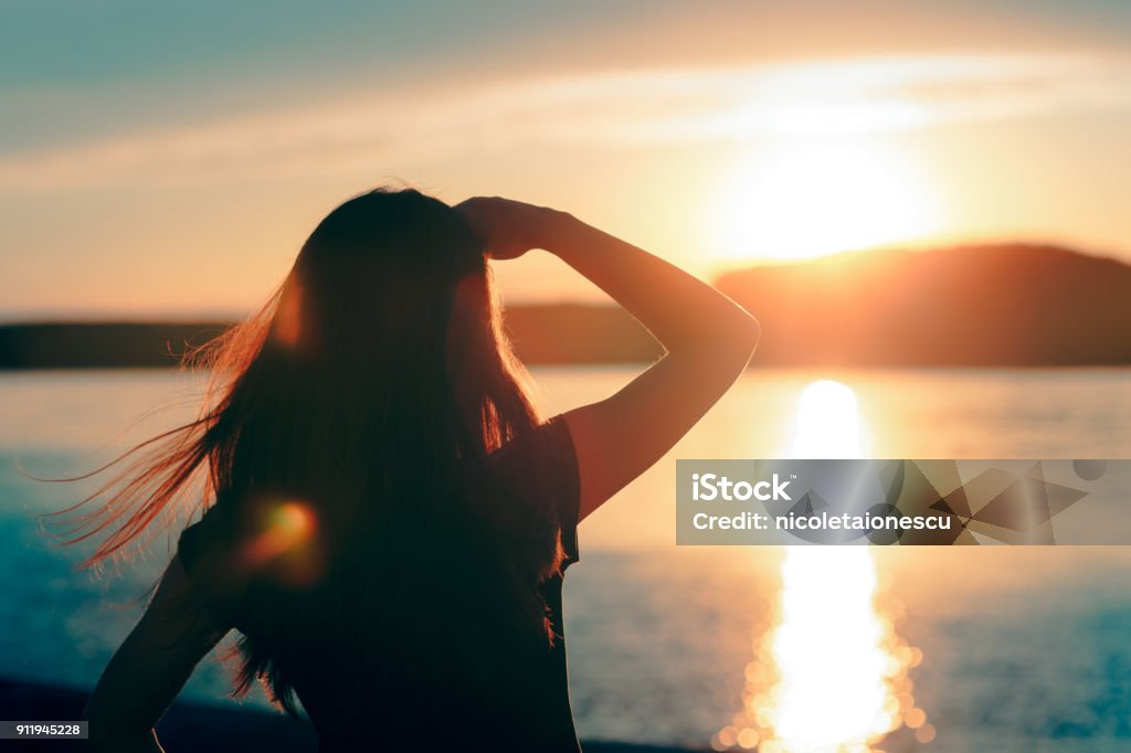 Happy Hopeful Woman Looking at the Sunset by the Sea Silhouette of a dreamer girl looking hopeful at the horizon Horizon Stock Photo