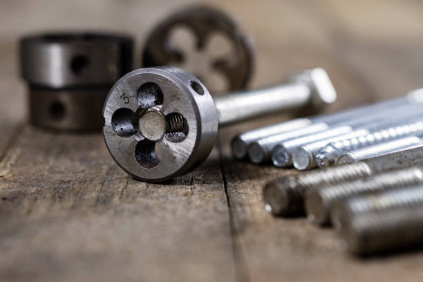 istock Metalwork tools on the workshop table. Threading dies and taps in an old dusty workshop. Black background. 911952972