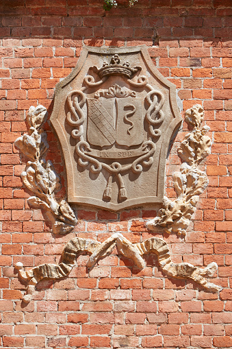BAROLO, ITALY - AUGUST 6: Barolo medieval castle coat of arms on red bricks wall in a sunny summer day on August 6, 2016 in Barolo, Italy. The Langhe area in Piedmont is Unesco World Heritage Site.