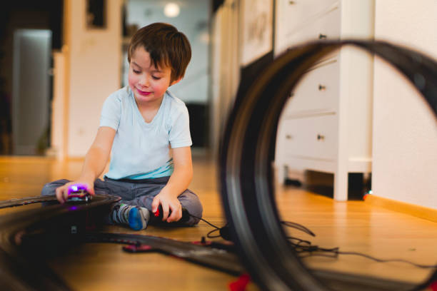 5 year old boy is playing with slot car model racing track 5 year old blond boy is playing with slot car model racing track indoor toy vehicle stock pictures, royalty-free photos & images