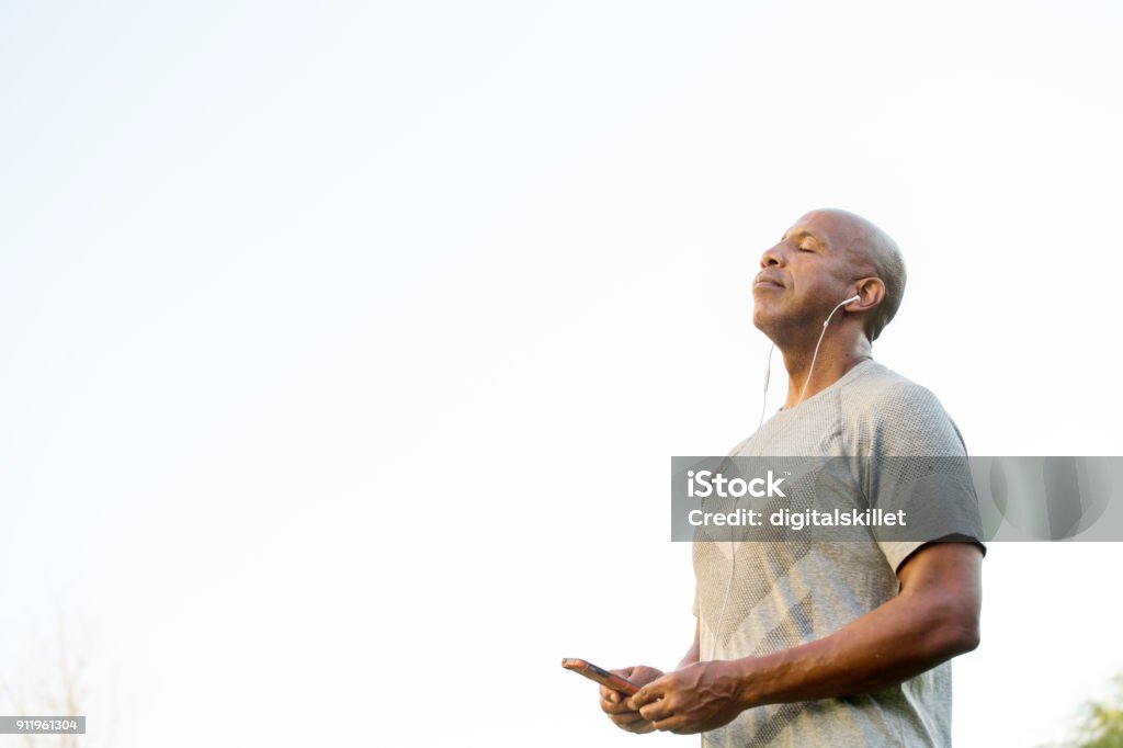 Fit African American man listening to music. Mature fit African American man listening to music. 55-59 Years Stock Photo