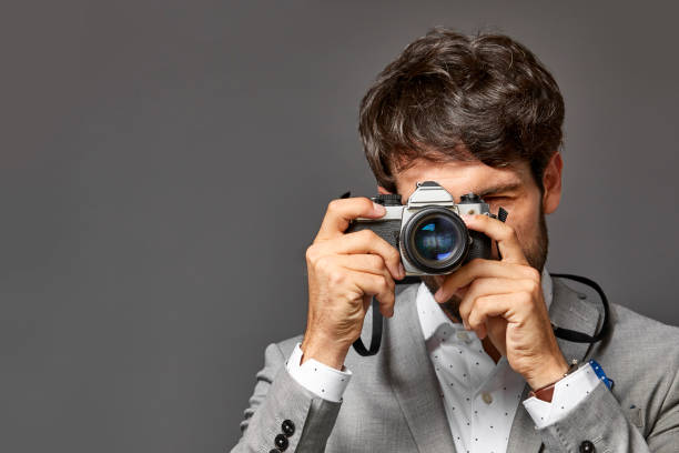 istock Businessman with camera against gray background 911963610