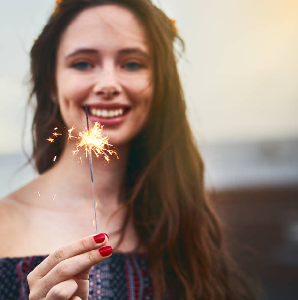 istock Beautiful teenage girl smiles brightly, holding lit sparkler firework 911963708