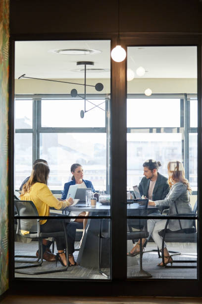 istock Business people in board room seen through glass 911963900