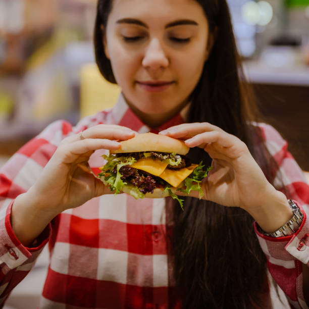 istock woman eat cheeseburger 911969906