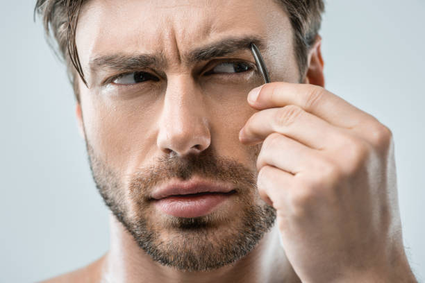 istock man plucking eyebrows with tweezers 911970844