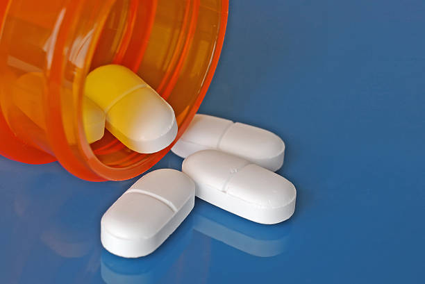 istock Pills coming out of prescription bottle on blue surface 91197237