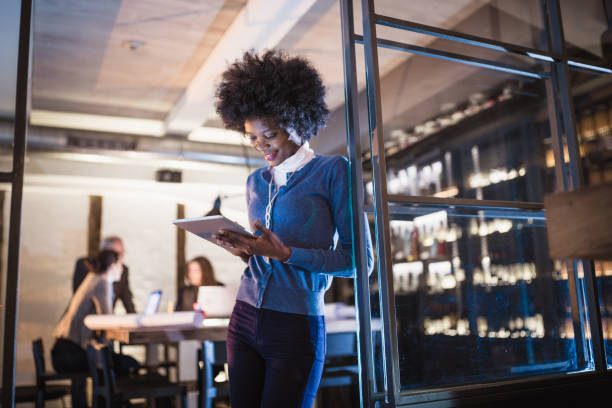 istock Working late. Young African-American woman architect using digital tablet in front of architecture studio. 911973258