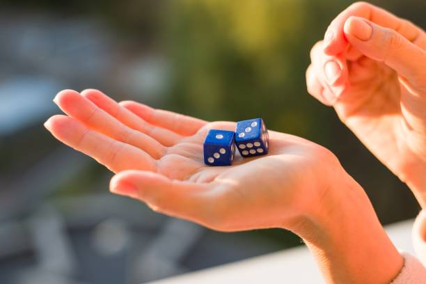 istock Dice 1 3 in the female hand, sunset background. Gambling devices. 911974392