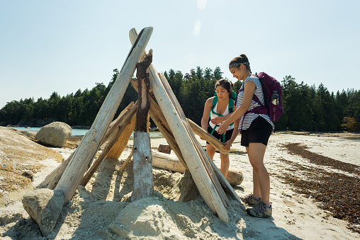 Eurasian sisters building driftwood shelter on Newcastle Island, Nanaimo, (Vancouver Island) British Columbia, Canada


