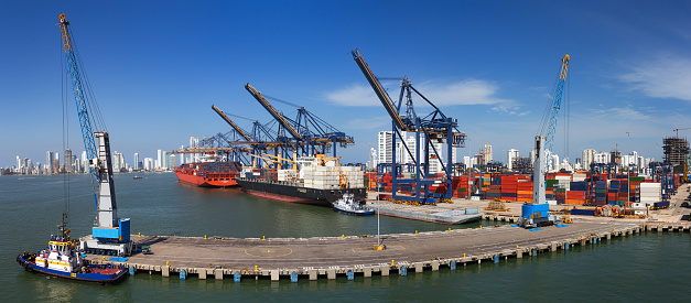 Panoramic view of a port activity with cargo ships, cranes and containers at the pier of the Port Of Cartagena, Colombia.