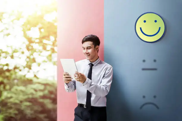 Photo of Customer Experience Concept, Happy Businessman Enjoying on digital Tablet with Smiley Face Rating for a Satisfaction Survey