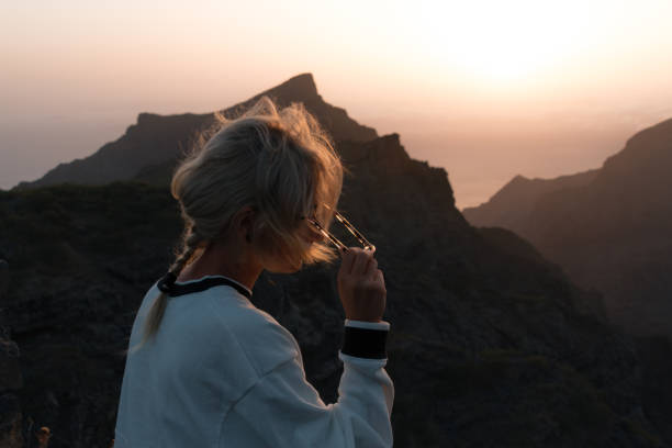 istock Young blond woman looking at rocky landscape with steep cliffs while sunset 911978274