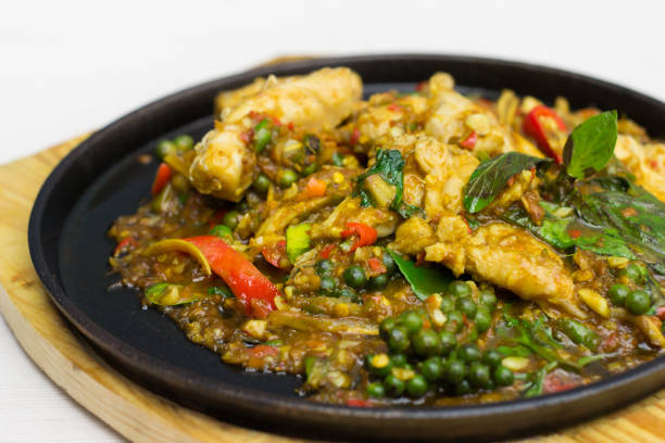 Stir-Fried spicy snapper in black plate on wooden board.