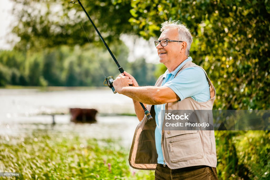 Senior man fishing Happy senior man is fishing on sunny day. Fishing Stock Photo