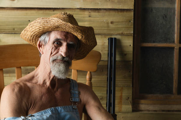 A good ol' country boy wearing his denim bib overalls and with his shotgun ready.