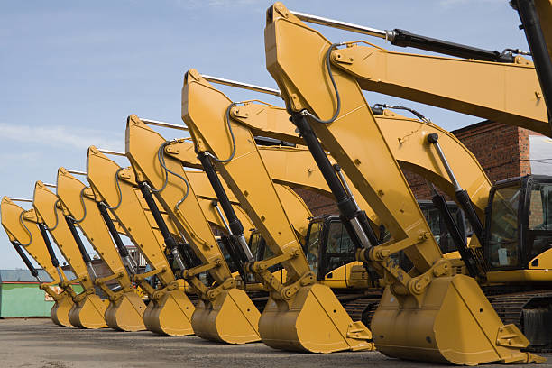 A row of yellow earth movers are parked in the open space stock photo