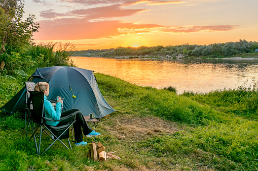 A girl in a camping with a tourist tent on the river bank. Russia. Oka river