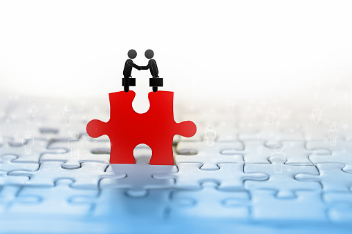 business concept background with two businessman handshake icon on red jigsaw with people connection in background idea for teamwork,support and partnership