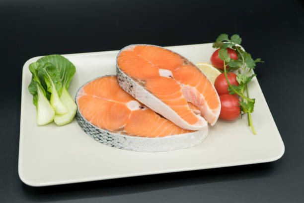 istock raw salmon steak with vegetable on plate, food and vegetable concept 911988698