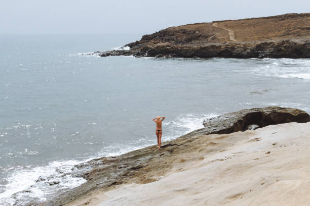 joven rubia en tangas posando en la playa de arena en el desierto - shirtless jeans women blond hair fotografías e imágenes de stock