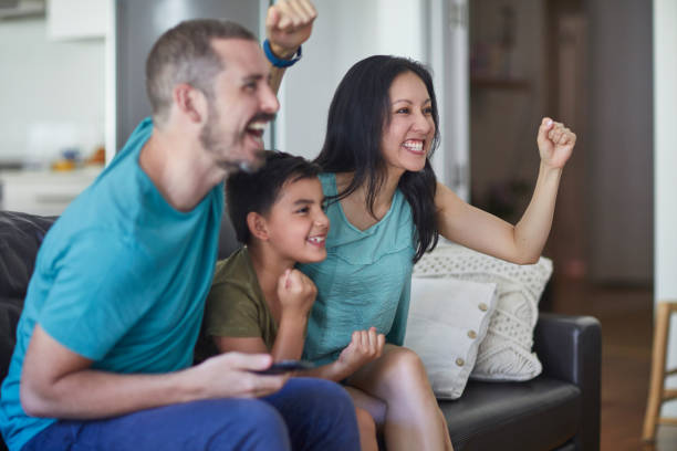 istock Family celebrating success together on sofa 911999460