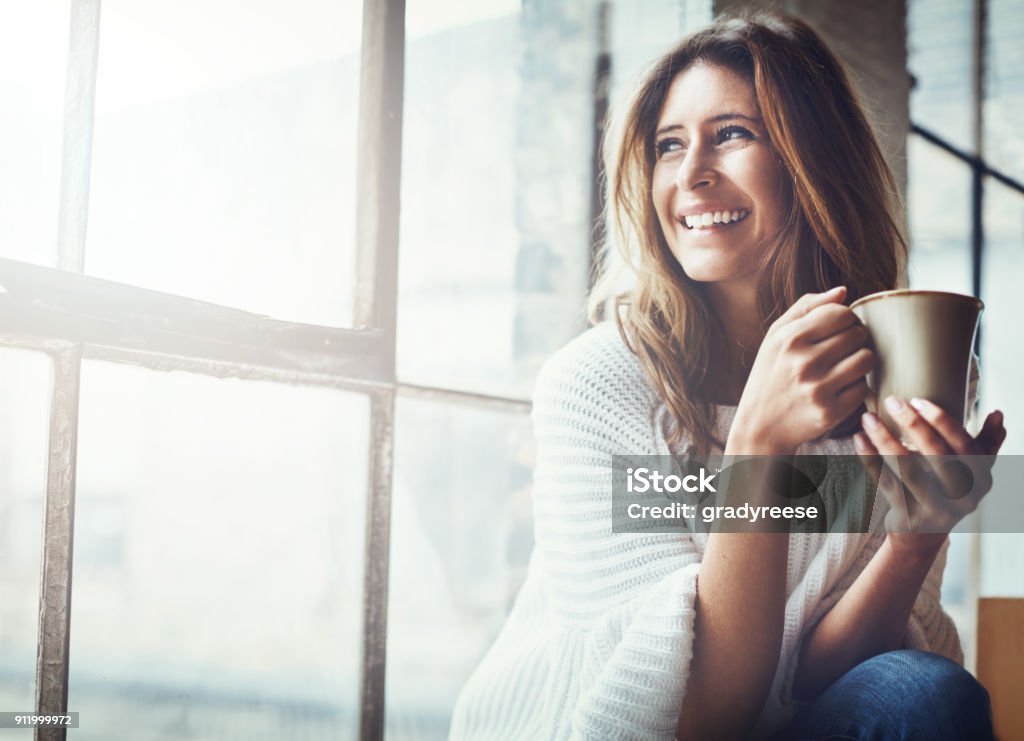 The sun's up and so is my mood Shot of an attractive young woman relaxing at home Women Stock Photo