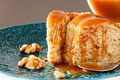 Piece of Banana cake with walnut and caramel fudge. Blue plate background. Close up. Selective focus.