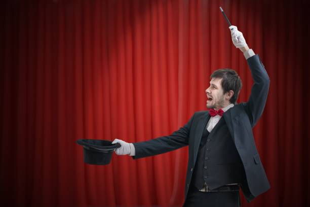 istock Happy magician or illusionist is showing magic trick. Red curtains in background. 912000732