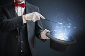 istock Magician or illusionist is showing magic trick. Blue stage light in background. 912003020