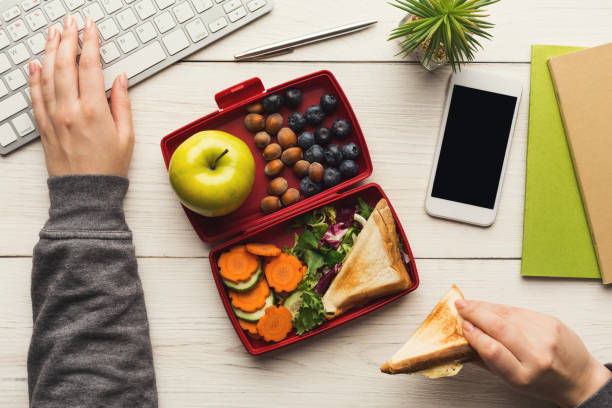 istock Woman eating healthy sandwich from lunch box at her working table 912007274