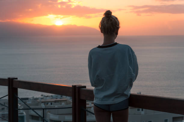 istock Young woman standing at view point and looking at sea while sunset 912020428